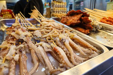 Bir tepsi ahtapot şişlerle sergilenir. Ahtapot parçalara ayrılır ve sosla servis edilir.