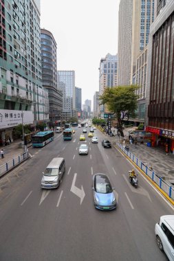 Chongqing Çin. Bir sürü insan ve trafiğin olduğu işlek bir şehir caddesi. Sokak yüksek binalarla dolu ve yolda bir sürü araba ve otobüs var.