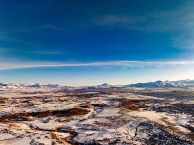 Birkaç bulutlu ve karlı manzaralı açık mavi bir gökyüzü. Gökyüzü engin ve kar zemini kaplıyor.
