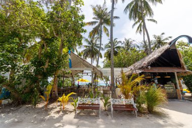 Bereketli palmiye ağaçları sahil kenarındaki bir kulübeyi çerçeveliyor. Beyaz banklar benekli güneşin altında rahatlamaya davetiye çıkarır. Kum, kırsal yerleşim yerinin etrafında yumuşak bir şekilde uzanıyor. Tropik yeşillik rüzgarda hafifçe sallanır.