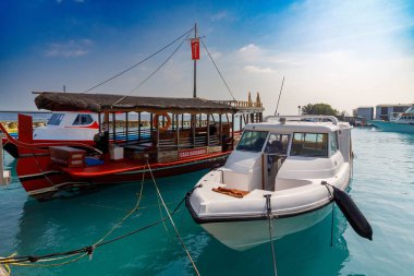 Temiz turkuaz su iki tekne alır. Kırmızı, sazdan yapılmış tekne beyaz bir teknenin yanında duruyor. Güneşli gökyüzü yukarıda yumuşak bulutlar gösteriyor. Sakin deniz aşağıdaki canlı renkleri yansıtır. Tatil için mükemmel, seyahat için.