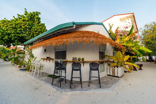 Sahil kenarındaki sazdan çatı ve bar tabureleri olan rahat bir kulübe. Beyaz duvarlar, yeşil süslemeler ve tropikal bitkiler cazibeyi arttırır. Güneşli sahne rahatlamaya ya da gündelik sohbete davetiye çıkarır. Seyahat ve tatil için mükemmel.
