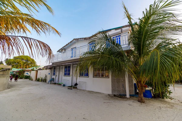 Sakin bir sahil evinin yakınında palmiye ağaçları yavaşça sallanıyor. Parlak mavi panjurlar beyaz boyalı duvarlarla tezat oluşturuyor. Sessiz sokak gezginleri huzur aramaya davet eder. Çocuklar yumuşak ışıkta oynarlar