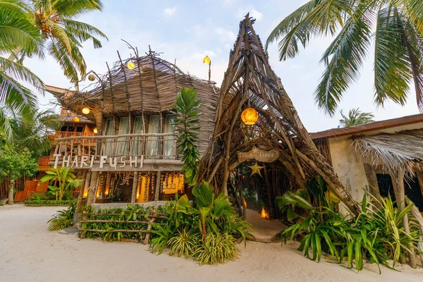 Tropikal kulübe sıcak, kırsal cazibeyi kucaklıyor. Bu çatı ve ahşap kirişler doğayla harmanlanmış. Palmiye ağaçları yumuşak, altın ışıkta sallanıyor. İşaret panosu barışçıl ve davetkar bir kaçışı işaret ediyor.