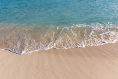 Kristal dalgalar altın kumu nazikçe öper. Güneş ışığı sakin turkuaz sularda parlar. Köpük izleri kıyıda yumuşak izler bırakır. Huzurlu bir an huzur ve gevşemeyi çağrıştırıyor.