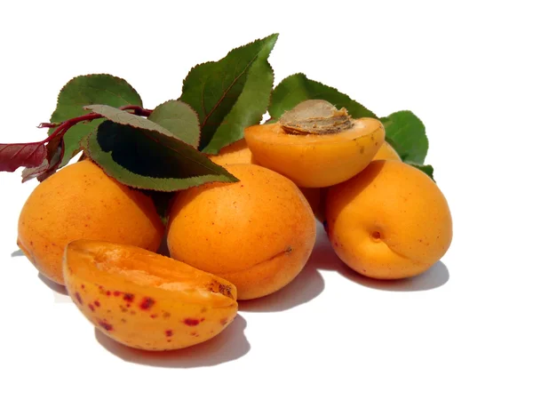 Rijp abrikozen met groene folders op een witte achtergrond close-up. — Stockfoto