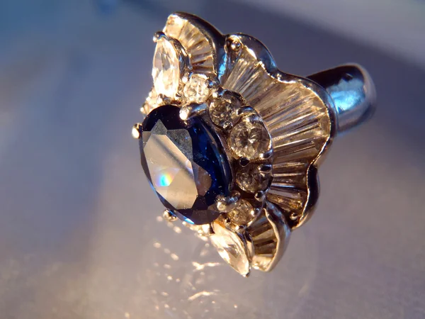Anel de prata com safira e zirconias cúbicos em um fundo azul, macro — Fotografia de Stock