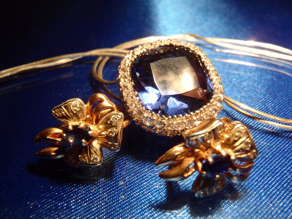 Gold earrings and pendent with sapphires on blue macro