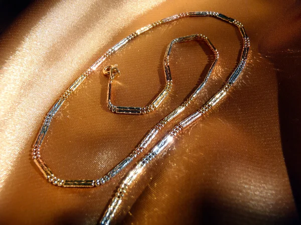 Золотая цепочка на золотом шелковом макро . — стоковое фото