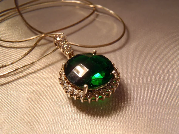 Pendent met een emerald aan een ketting, macro. — Stockfoto