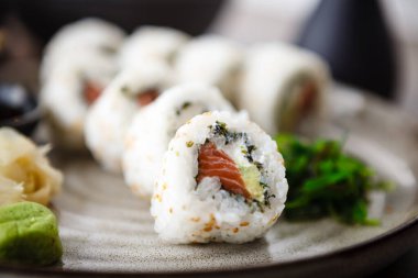 Suşi maki Philadelphia 'yı somon, krem peynir ve yemek çubuğu, soya sosu, wasabi ve zencefilli avokado ile yuvarlıyor. Geleneksel Japon deniz ürünleri modern restoranda öğle yemeği için servis edilir.