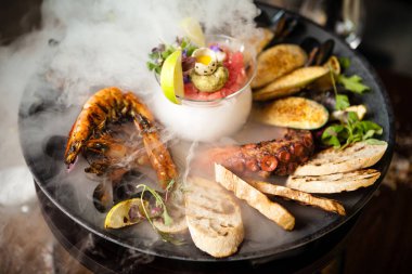 2-4 kişi için deniz ürünleri tabağı. Ahtapot, mavi midye, pişmiş yeşil midye, ızgara kaplan karidesi, ton balığı. Lezzetli deniz ürünleri modern gurme restoranında öğle yemeğinde servis edilir..