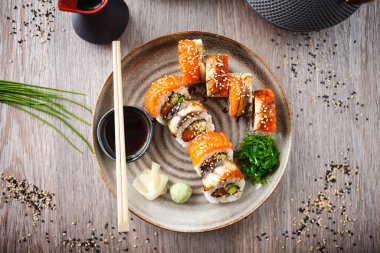 Somon, yılan balığı, avokado soslu suşi çubuklu salatalık, soya sosu, wasabi ve zencefil. Japon geleneksel balık yemekleri modern gurme restoranında öğle yemeği için servis edilir..