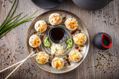 Pişmiş suşi maki ruloları, karides ve yengeç ile birlikte yemek çubuğu, soya sosu, wasabi ve zencefil. Japon geleneksel balık yemekleri modern gurme restoranında öğle yemeği için servis edilir..