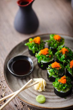 Yengeç, yosun salatası ve yemek çubuğu, soya sosu, wasabi ve zencefilli uçan balık yumurtası ile suşi maki ruloları. Geleneksel Japon deniz ürünleri modern gurme restoranında öğle yemeği olarak servis edilir..