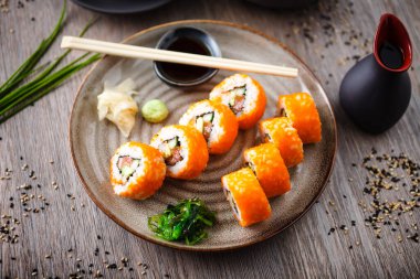 Somon, avokado, salatalık, yemek çubuğu, soya sosu, wasabi ve zencefilli bir tabakta uçan balık yumurtası. Japon geleneksel yemekleri modern gurme restoranında öğle yemeği olarak servis edilir..