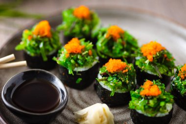 Yengeç, yosun salatası ve yemek çubuğu, soya sosu, wasabi ve zencefilli uçan balık yumurtası ile suşi maki ruloları. Geleneksel Japon deniz ürünleri modern gurme restoranında öğle yemeği olarak servis edilir.