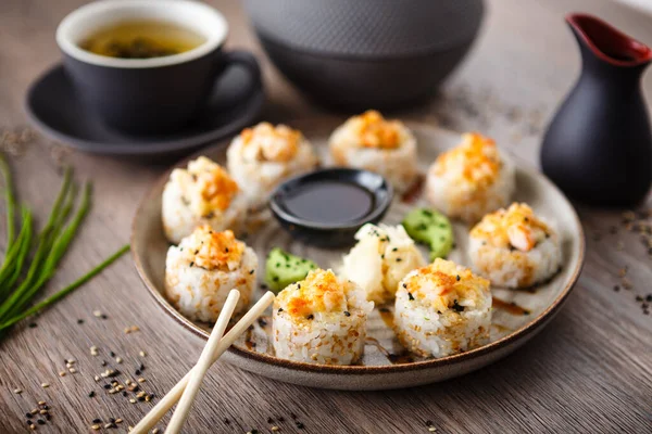 Pişmiş suşi maki ruloları, karides ve yengeç ile birlikte yemek çubuğu, soya sosu, wasabi ve zencefil. Japon geleneksel balık yemekleri modern gurme restoranında öğle yemeği için servis edilir. — Stok fotoğraf