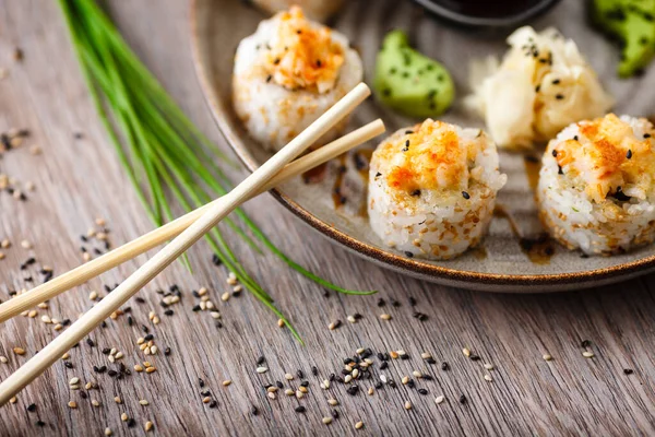 Bakade sushi maki rullar med räkor och krabba på en tallrik med ätpinnar, sojasås, wasabi och ingefära. Japansk traditionell fisk mat närbild serveras till lunch i modern gourmet restaurang — Stockfoto