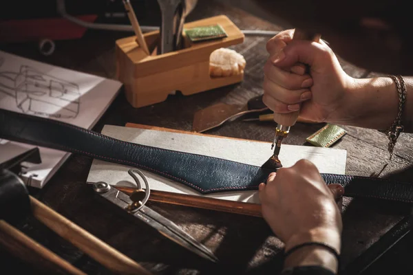 Leather handbag craftsman at work in a vintage workshop. Small business concept