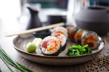 Ton balıklı suşi maki böreği, uçan balık havyarı, yengeç, yemek çubuğu, soya sosu, wasabi ve zencefilli avokado. Japon geleneksel yemekleri modern gurme restoranında öğle yemeği için servis edilir..