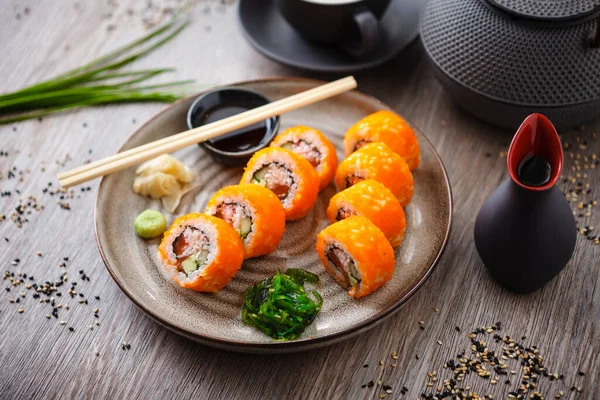 Suşi maki, somon, avokado, salatalık, yengeç ve uçan balık yumurtasını soya sosu, wasabi ve zencefilli bir tabakta California Futomaki yuvarlıyor. Japon geleneksel deniz ürünleri restoranı — Stok fotoğraf
