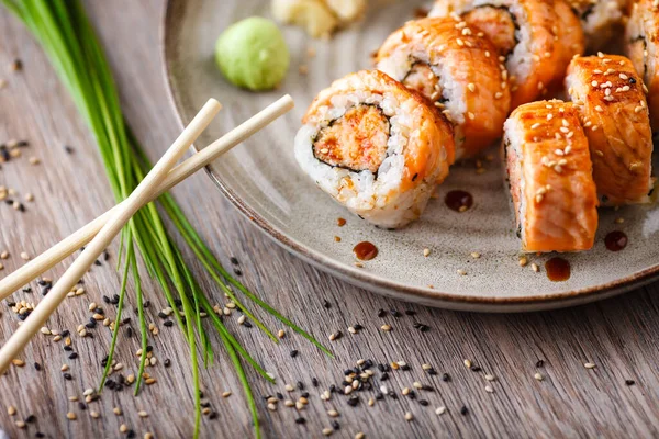 Gebakken sushi maki broodjes met zalm, krab en pittige saus op een bord met stokjes, sojasaus, wasabi en gember. Japanse traditionele visgerechten close-up geserveerd voor de lunch in modern gastronomisch restaurant — Stockfoto
