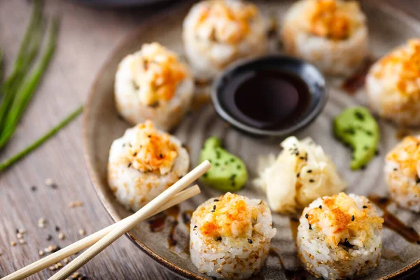 Gebakken sushi maki broodjes met garnalen en krab op een bord met stokjes, sojasaus, wasabi en gember. Japanse traditionele visgerechten close-up geserveerd voor de lunch in modern gastronomisch restaurant — Stockfoto