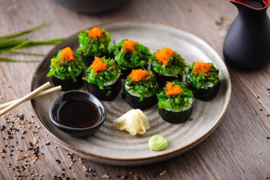 Yengeç, yosun salatası ve yemek çubuğu, soya sosu, wasabi ve zencefilli uçan balık yumurtası ile suşi maki ruloları. Geleneksel Japon deniz ürünleri modern gurme restoranında öğle yemeği olarak servis edilir.