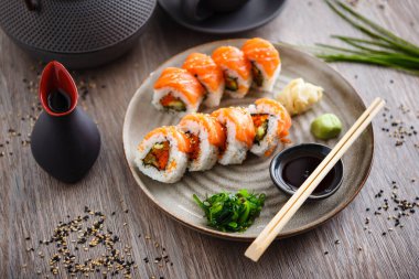 Somon, avokado, uçan balık yumurtası ve yemek çubuğu, soya sosu, wasabi ve zencefilli salatalık. Geleneksel Japon deniz ürünleri modern restoranda öğle yemeği için servis edilir.