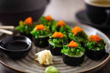 Yengeç, yosun salatası ve yemek çubuğu, soya sosu, wasabi ve zencefilli uçan balık yumurtası ile suşi maki ruloları. Geleneksel Japon deniz ürünleri modern gurme restoranında öğle yemeği olarak servis edilir..