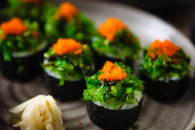 Yengeç, yosun salatası ve yemek çubuğu, soya sosu, wasabi ve zencefilli uçan balık yumurtası ile suşi maki ruloları. Geleneksel Japon deniz ürünleri modern gurme restoranında öğle yemeği olarak servis edilir..