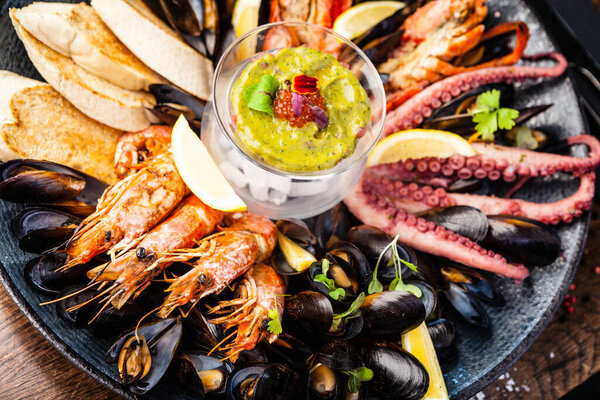 Тарелка для сифуда на 2-4 человека. Лобстер, осьминог, голубые мидии, креветки-короли Аргентины, тартар с тунцом. Вкусные здоровые традиционные блюда крупным планом подаются на обед в ресторане современной изысканной кухни.