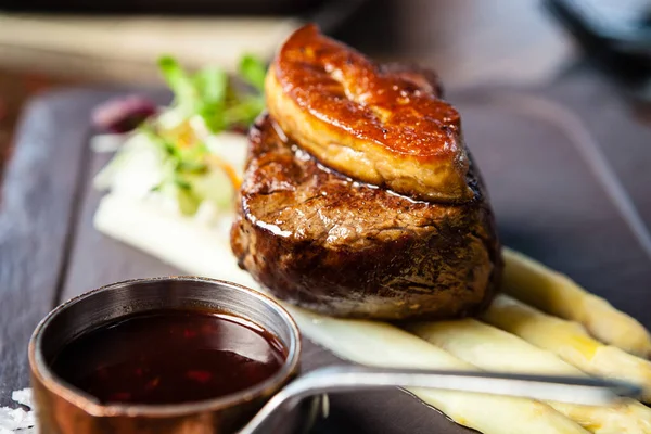 Tournedos Rossini. Foie gras, Black Angus beef tenderloin, white asparagus, red wine sauce. Delicious healthy traditional food closeup served for lunch in modern gourmet cuisine restaurant.