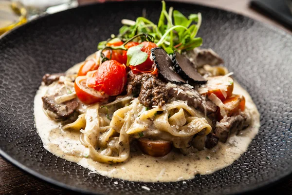 Pasta negra de tagliatelle de res Angus con trufas negras frescas y parmegano. Delicioso primer plano de comida tradicional saludable servido para el almuerzo en el restaurante de cocina gourmet moderna — Foto de Stock