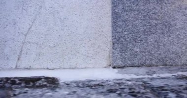 Üzerinde gri beton bir levha olan gri bir duvar. Levha çatlamış ve birkaç parçası eksik.