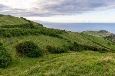 Okyanus manzaralı bir yamaç. Çimler yeşil ve gökyüzü bulutlu Sete Cidades, Azores 'de.
