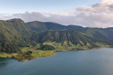 Sete Cidades, Azores 'in arka planında bir göl olan güzel bir dağ sırası. Dağlar ağaçlarla kaplı ve göl sakin ve berrak. Sahne huzurlu ve sakin, dağlarla birlikte.