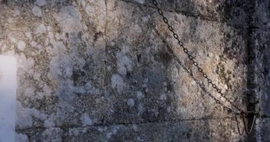 The Romanesque church bell tower is old and has a lot of moss growing on it. The sky is clear and blue