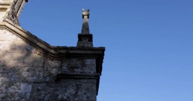 A Romanesque church steeple with a cross on top. The sky is blue and clear