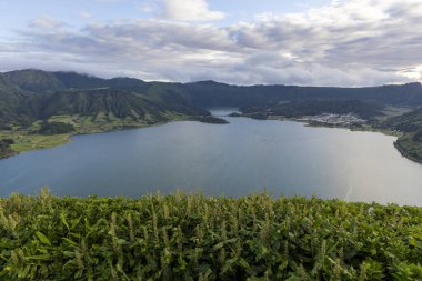 Sete Cidades, Azores 'in arka planında yeşil bir çit olan güzel bir göl. Göl sakin ve huzurlu, ve yeşil çit doğaya bir dokunuş ekliyor.