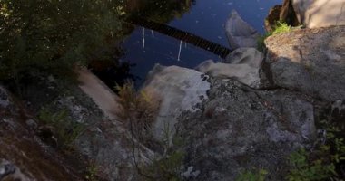 Nehir manzaralı bir köprü gibi. Köprü ahşaptır ve metal bir çerçeveye sahiptir. Su sakin ve berrak. Yukarı kaldır..