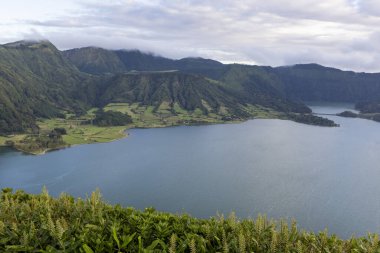 Sete Cidades, Azores 'in arka planında dağlar olan güzel bir göl. Su sakin ve berrak. Dağlar ağaçlarla kaplı ve göl yeşil tepelerle çevrili..