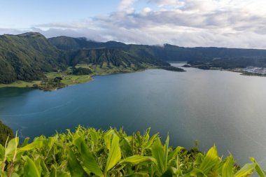 Sete Cidades, Azores 'in arka planında dağlar olan güzel bir göl. Su sakin ve berrak. Dağlar ağaçlarla kaplı ve gökyüzü mavi