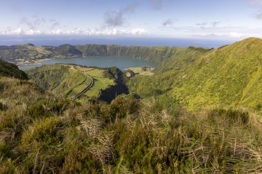 Sete Cidades, Azores 'in arka planında bir göl olan güzel bir dağ manzarası. Manzara sakin ve huzurlu. Yeşillik yeşili çimenler ve ağaçlar doğayla uyum ve sükunet duygusu yaratır.