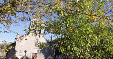 Önünde haç olan bir kilise. Ağaçlardaki yapraklar renk değiştiriyor. Gökyüzü mavi ve berrak