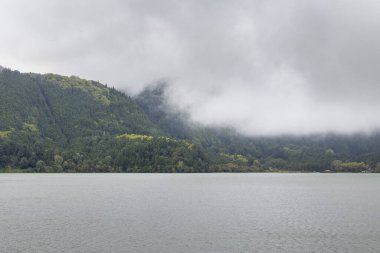 Arka planda göl olan bulutlu bir gün. Gökyüzü bulutlu ve su sakin.