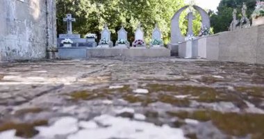 Taş duvarı ve taş yolu olan bir mezarlık. Yol mezar taşlarıyla kaplı ve yol boyunca birkaç küçük mezar taşı var.