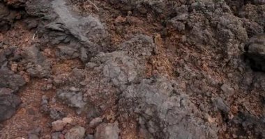 Arka planda bir su kütlesi olan kayalık bir kıyı şeridi. Kayalar büyük ve pürüzlü. Sahneye sert ve vahşi bir görünüm kazandırıyor. İzleme görüntüsü.