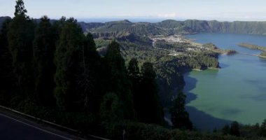 Sete Cidades 'teki bir kraterde güzel bir volkanik göl. Göl, Azores 'in Sao Miguel adasında açık güneşli bir günde ağaçlar ve okyanuslarla çevrilidir. Sağa çevir.